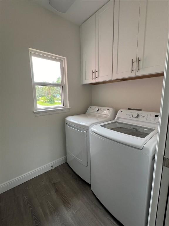 clothes washing area with independent washer and dryer, cabinets, and dark hardwood / wood-style floors