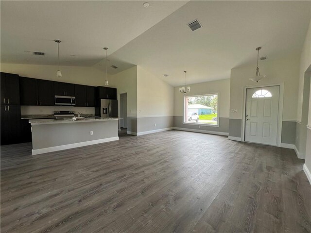 unfurnished living room with dark wood-type flooring, an inviting chandelier, and high vaulted ceiling