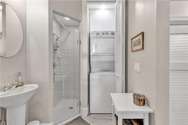 bathroom featuring stacked washer / drying machine and a shower with door