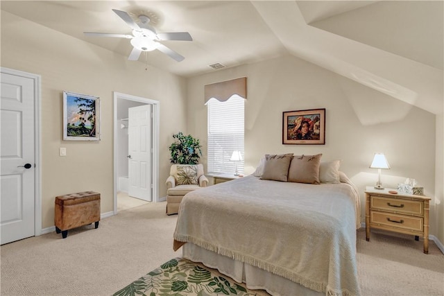 bedroom featuring vaulted ceiling, light colored carpet, ensuite bath, and ceiling fan