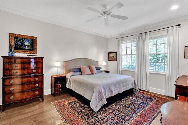 bedroom featuring ceiling fan, ornamental molding, and light wood-type flooring