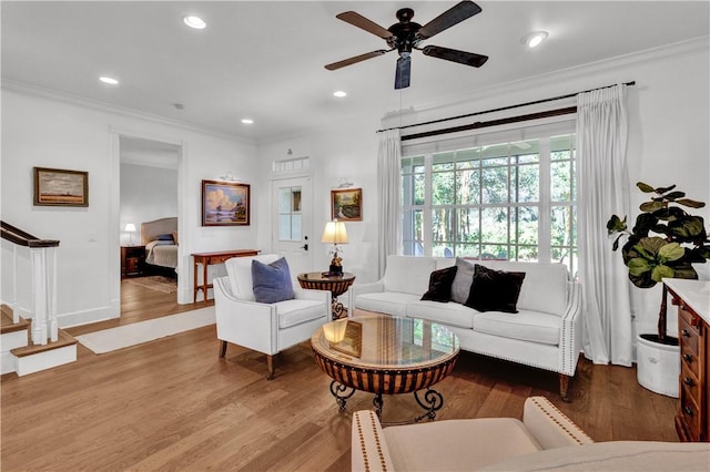 living room with light hardwood / wood-style floors, ceiling fan, and crown molding