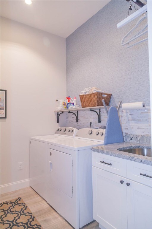 laundry room with washing machine and dryer, cabinets, and light wood-type flooring