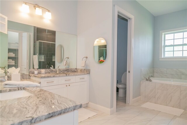 bathroom with vanity, toilet, and a relaxing tiled tub