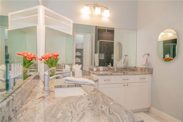 bathroom with a shower with shower door, vanity, and tile patterned flooring