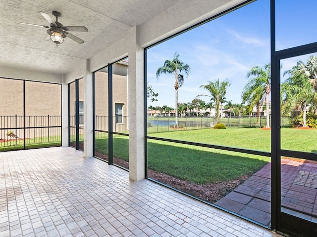 unfurnished sunroom with a water view and ceiling fan