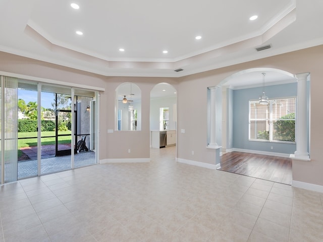 unfurnished living room featuring ceiling fan, a tray ceiling, ornamental molding, and light hardwood / wood-style flooring