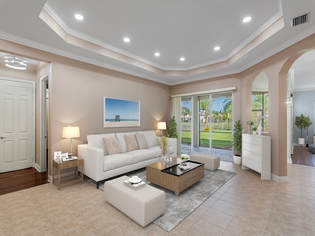 living room with ornamental molding, light hardwood / wood-style floors, and a raised ceiling