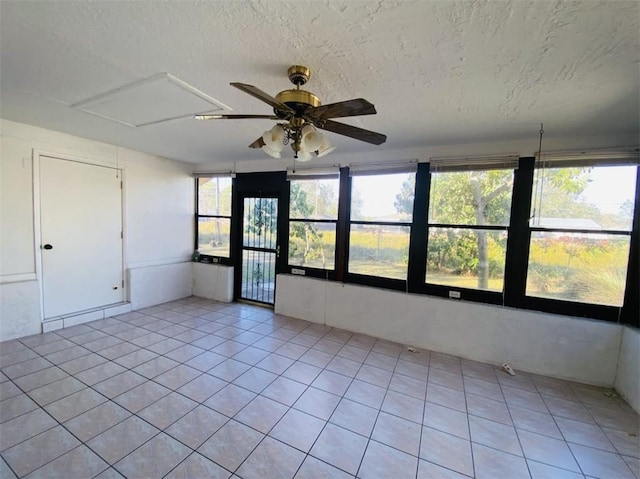 unfurnished sunroom featuring ceiling fan and a healthy amount of sunlight