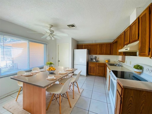 kitchen featuring a breakfast bar, white appliances, ceiling fan, light tile patterned floors, and a center island