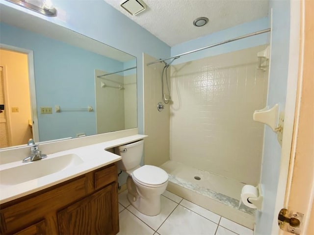 bathroom with a tile shower, tile patterned floors, a textured ceiling, toilet, and vanity