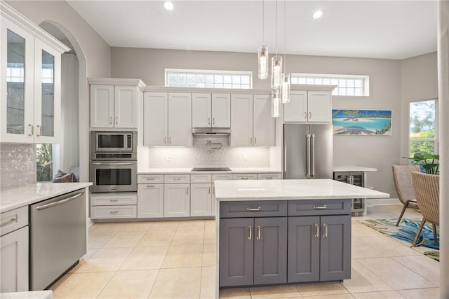 kitchen featuring stainless steel appliances, light stone counters, pendant lighting, gray cabinets, and white cabinets