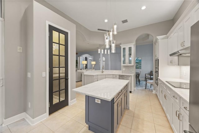 kitchen featuring hanging light fixtures, kitchen peninsula, decorative backsplash, a kitchen island, and white cabinetry