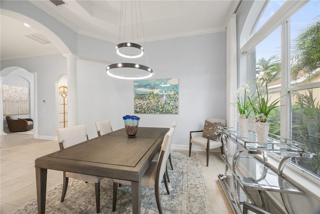 tiled dining area with a raised ceiling and crown molding