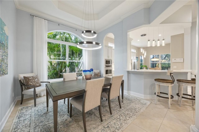 dining space with a notable chandelier, a raised ceiling, light tile patterned floors, and crown molding