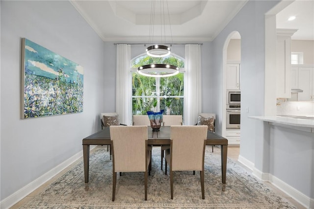 dining room with a tray ceiling and ornamental molding