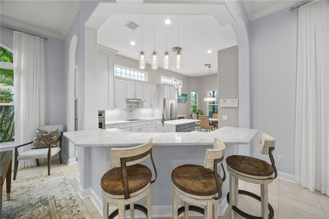 kitchen featuring stainless steel appliances, hanging light fixtures, a breakfast bar area, and an island with sink