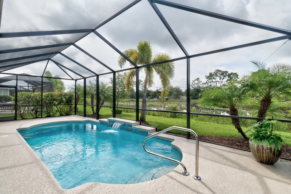 view of pool featuring a patio, glass enclosure, and pool water feature