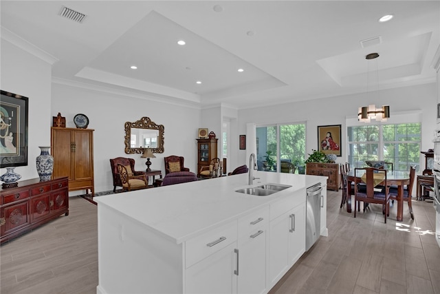 kitchen with white cabinets, sink, a kitchen island with sink, and a raised ceiling