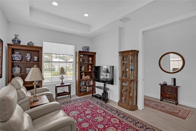 living room featuring light hardwood / wood-style flooring and a tray ceiling