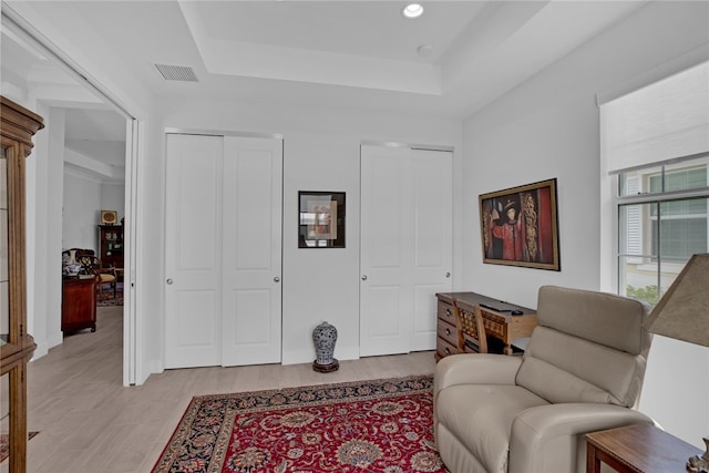 sitting room featuring light wood-type flooring and a tray ceiling