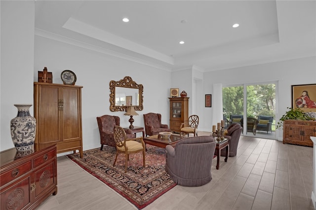 living room with light hardwood / wood-style floors and a tray ceiling