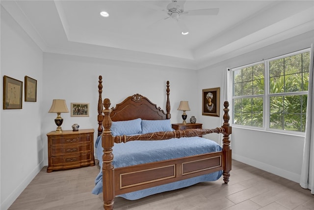 bedroom with light hardwood / wood-style floors, a tray ceiling, and ceiling fan