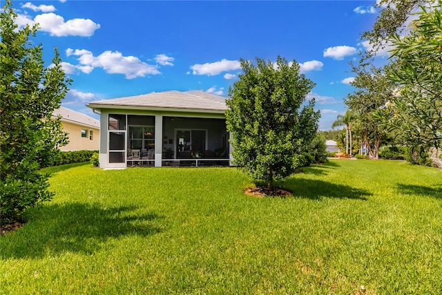 back of property with a lawn and a sunroom