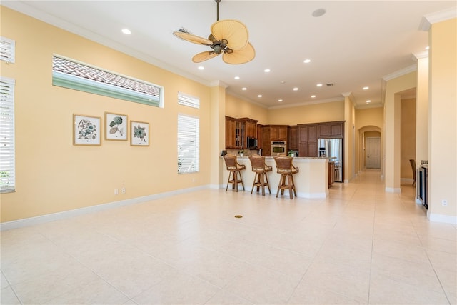 kitchen featuring stainless steel appliances, a kitchen bar, light tile patterned floors, and crown molding