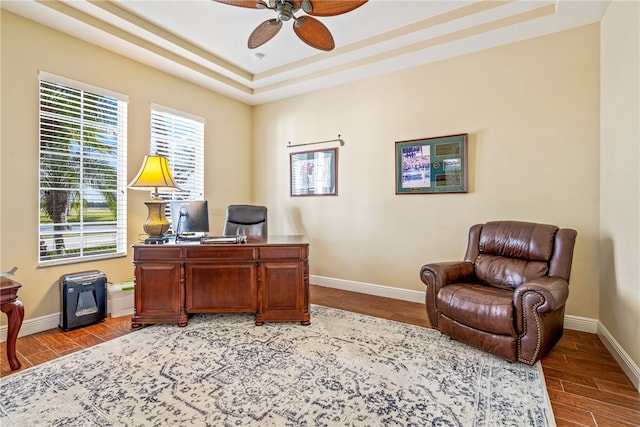 office space with a tray ceiling, ceiling fan, and light hardwood / wood-style flooring