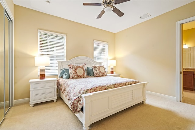 bedroom featuring a closet, light carpet, ceiling fan, and ensuite bathroom