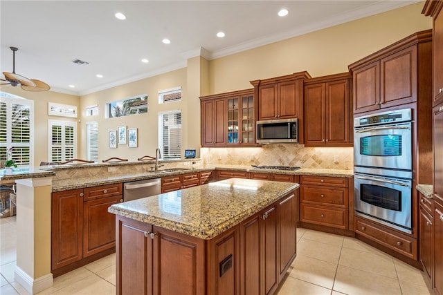 kitchen with stainless steel appliances, kitchen peninsula, sink, light tile patterned floors, and a kitchen island