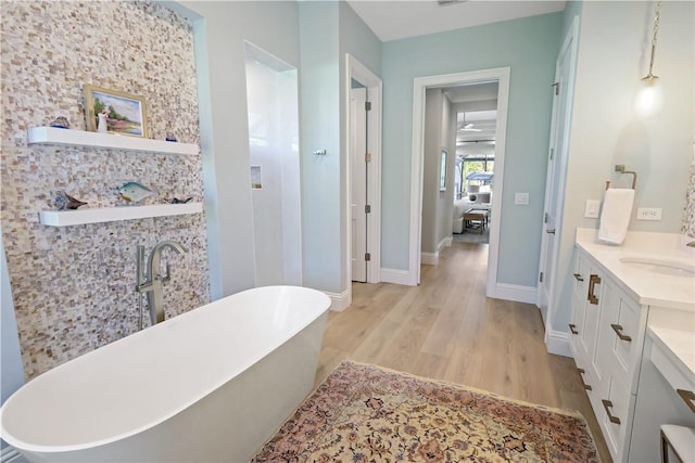 bathroom with a washtub, vanity, and wood-type flooring