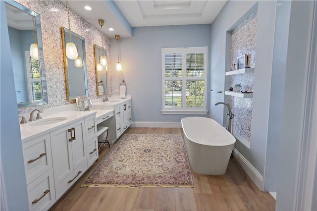 bathroom featuring hardwood / wood-style floors, backsplash, vanity, a tray ceiling, and a tub