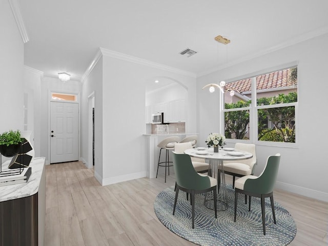 dining area with crown molding and light hardwood / wood-style flooring