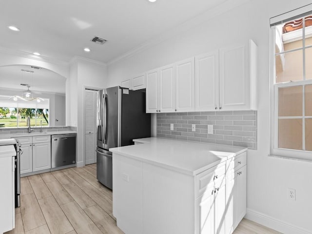 kitchen with sink, ornamental molding, appliances with stainless steel finishes, decorative backsplash, and white cabinets