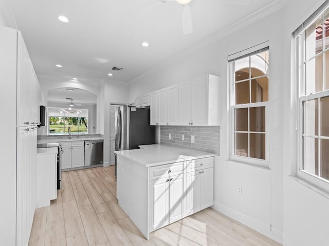 kitchen featuring crown molding, ceiling fan, white cabinetry, stainless steel appliances, and tasteful backsplash