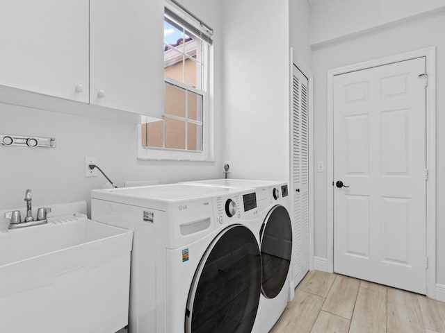 washroom featuring separate washer and dryer, sink, light hardwood / wood-style floors, and cabinets