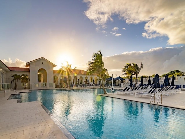 pool at dusk with a patio area