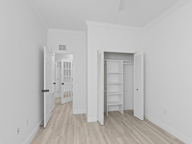 unfurnished bedroom featuring crown molding, light hardwood / wood-style floors, and a closet