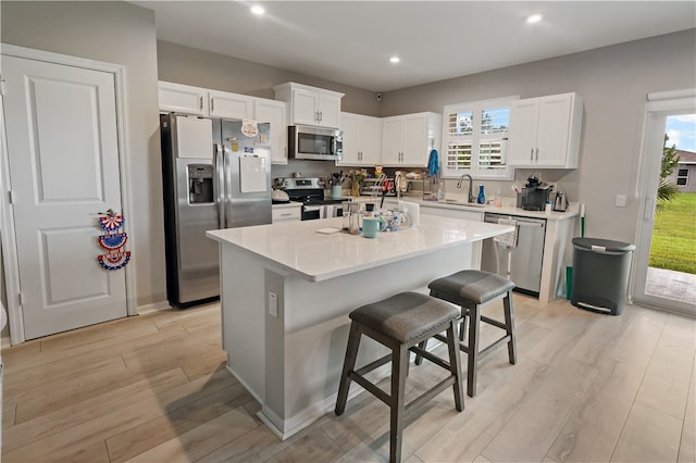 kitchen featuring stainless steel appliances, a breakfast bar, a kitchen island, and light hardwood / wood-style flooring