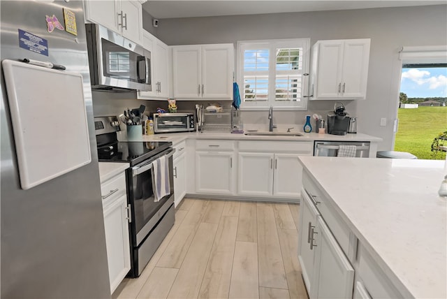 kitchen with a healthy amount of sunlight, appliances with stainless steel finishes, sink, and light hardwood / wood-style flooring