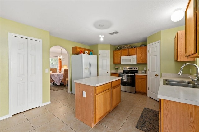 kitchen featuring sink, white appliances, a center island, and light tile patterned floors