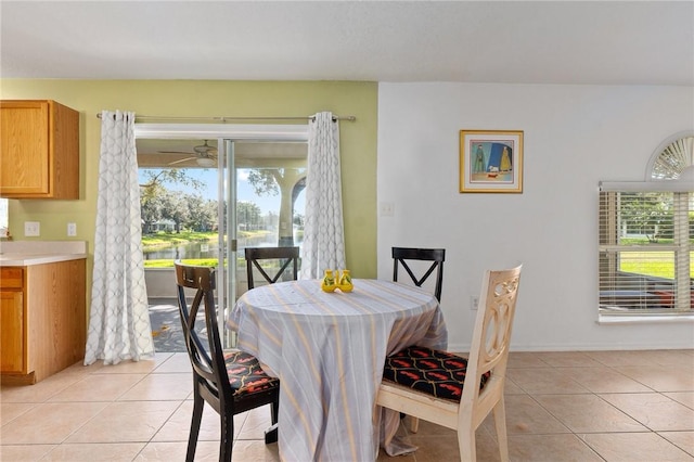 tiled dining room featuring a water view and ceiling fan