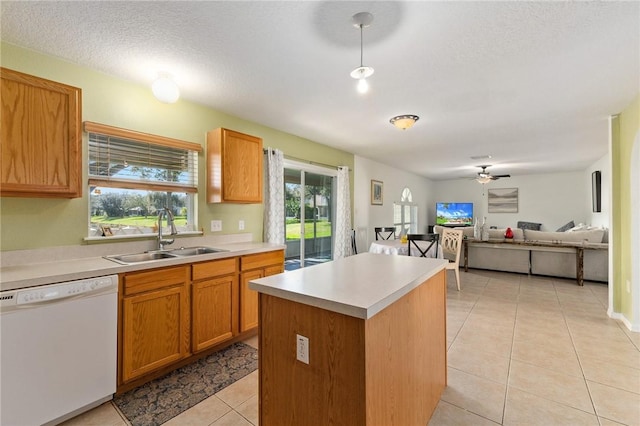 kitchen featuring sink, dishwasher, a center island, a textured ceiling, and light tile patterned flooring