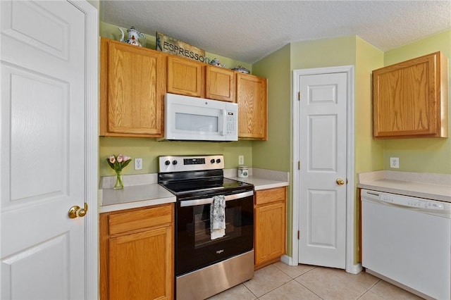 kitchen with white appliances, a textured ceiling, and light tile patterned floors