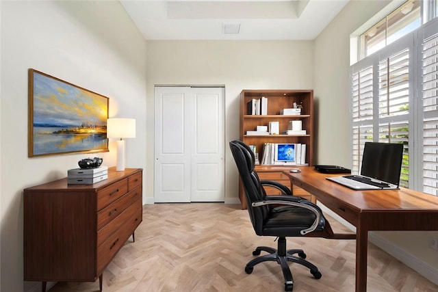 home office with a tray ceiling and light parquet floors