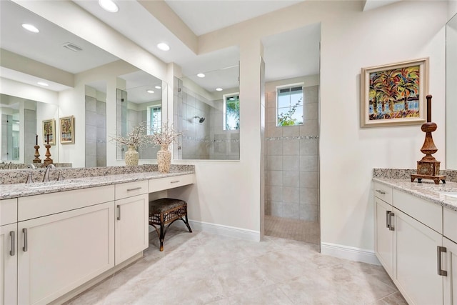 bathroom with a tile shower and vanity