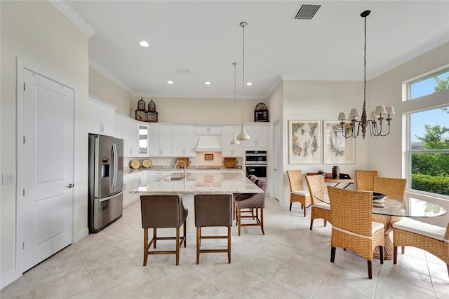 kitchen featuring light stone countertops, white cabinetry, a kitchen island with sink, and appliances with stainless steel finishes