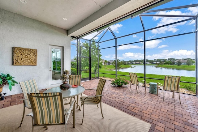 view of patio with a lanai and a water view